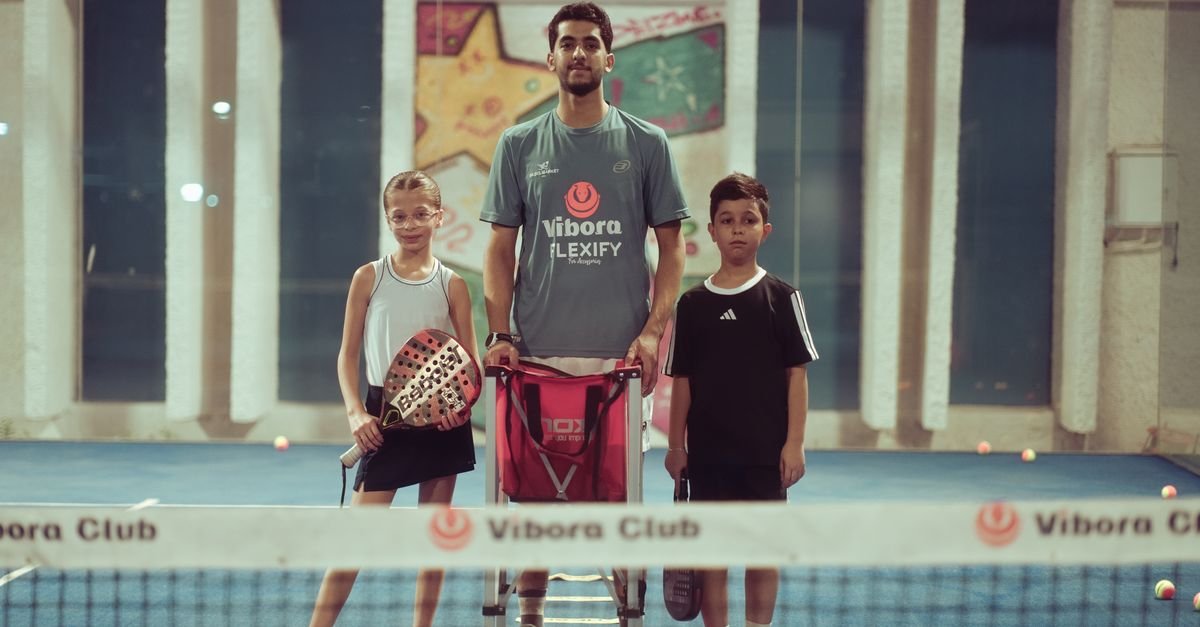 Tennis coach working with two young players