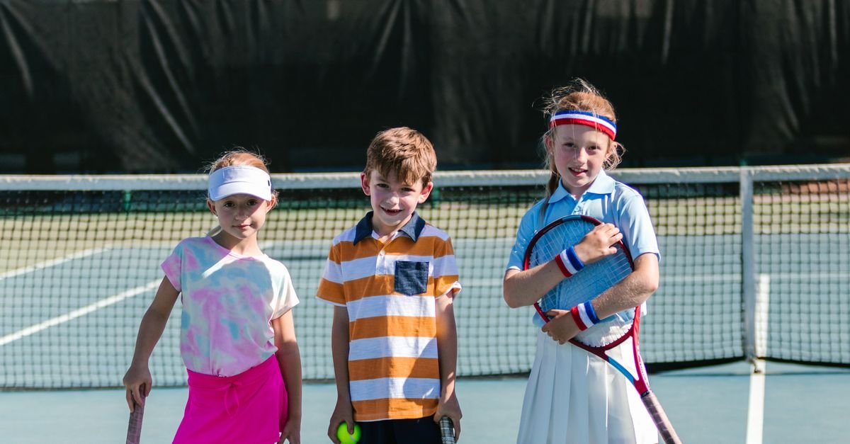 Group of children with tennis rackets in a coaching circle